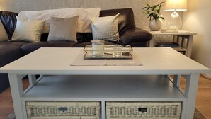 Un salon avec une table basse blanche, un canapé en cuir noir et une lampe sur une table d’appoint.