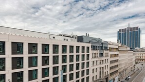 Een modern hotelgebouw met een raster van ramen, een opvallend blauw bord en een uitzicht op een hoge wolkenkrabber in de verte.