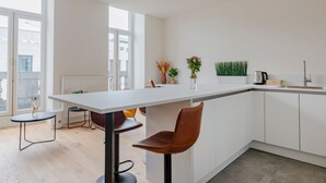 Een moderne keuken met een wit aanrecht, een koffieapparaat en een potplant.