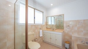 A modern bathroom with a toilet, sink, and shower area. - Moondance 2 - Yamba (Yamba)