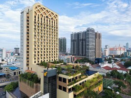 Un hotel de gran altura con una fachada de ventanas en cuadrícula, un jardín en la azotea y vistas a la ciudad.