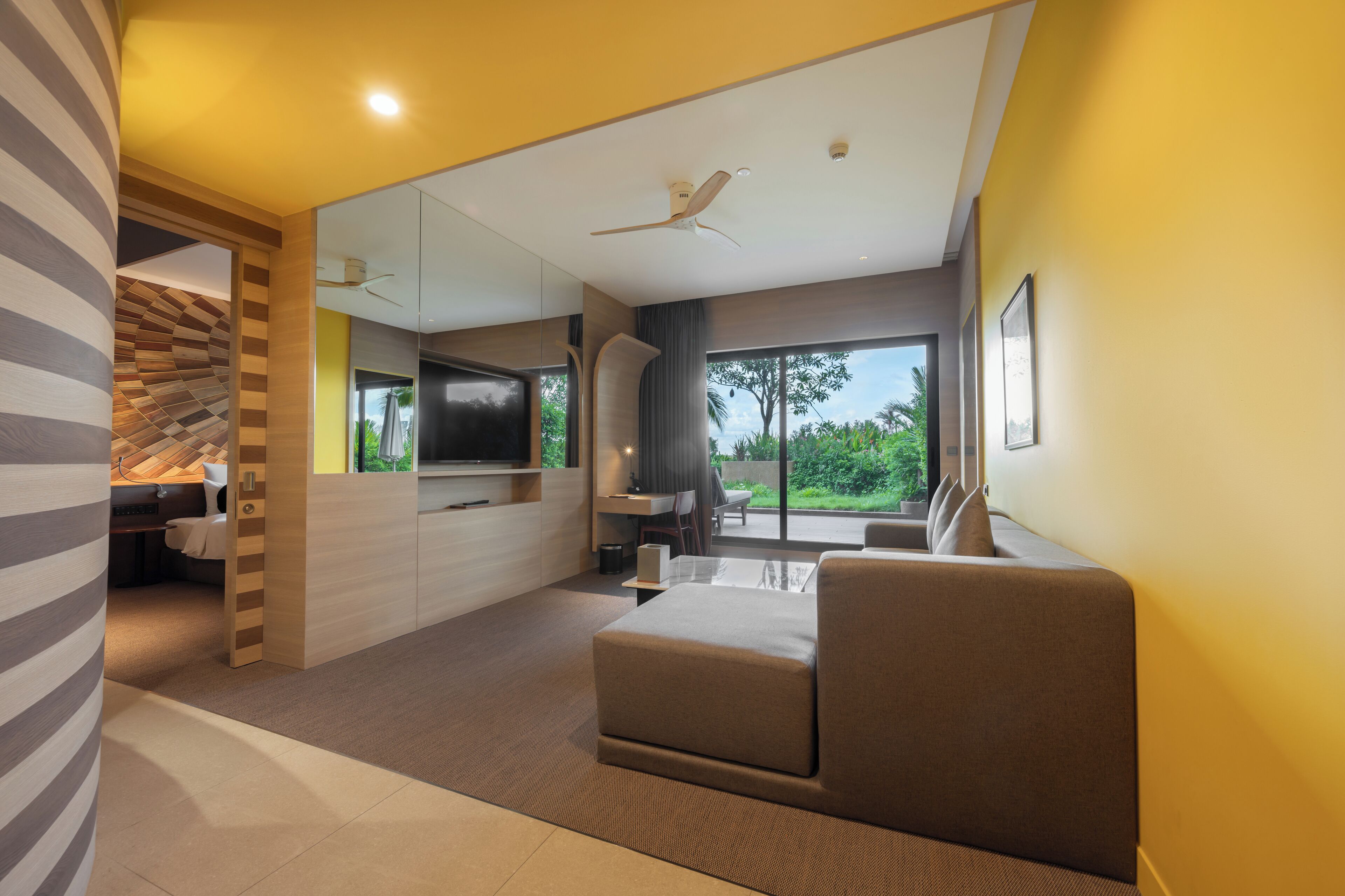 A modern living room with a sofa, a flat-screen TV, and a dining area with a table and chairs.