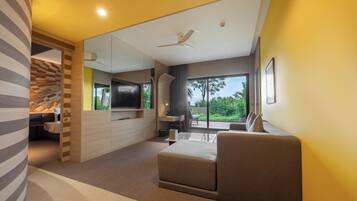 A modern living room with a sofa, a flat-screen TV, and a dining area with a table and chairs.