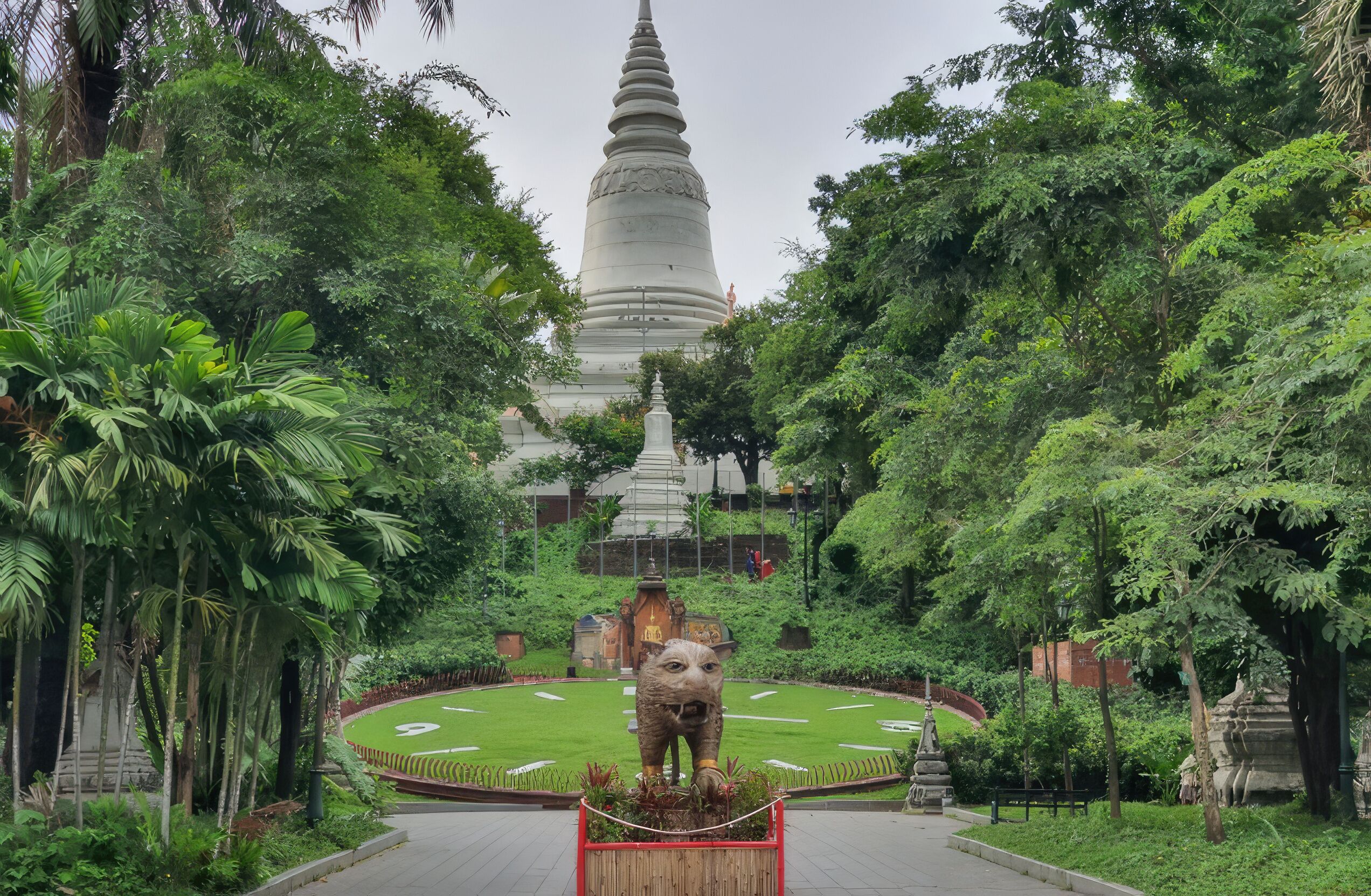 A large white stupa surrounded by lush greenery and a central elephant statue.