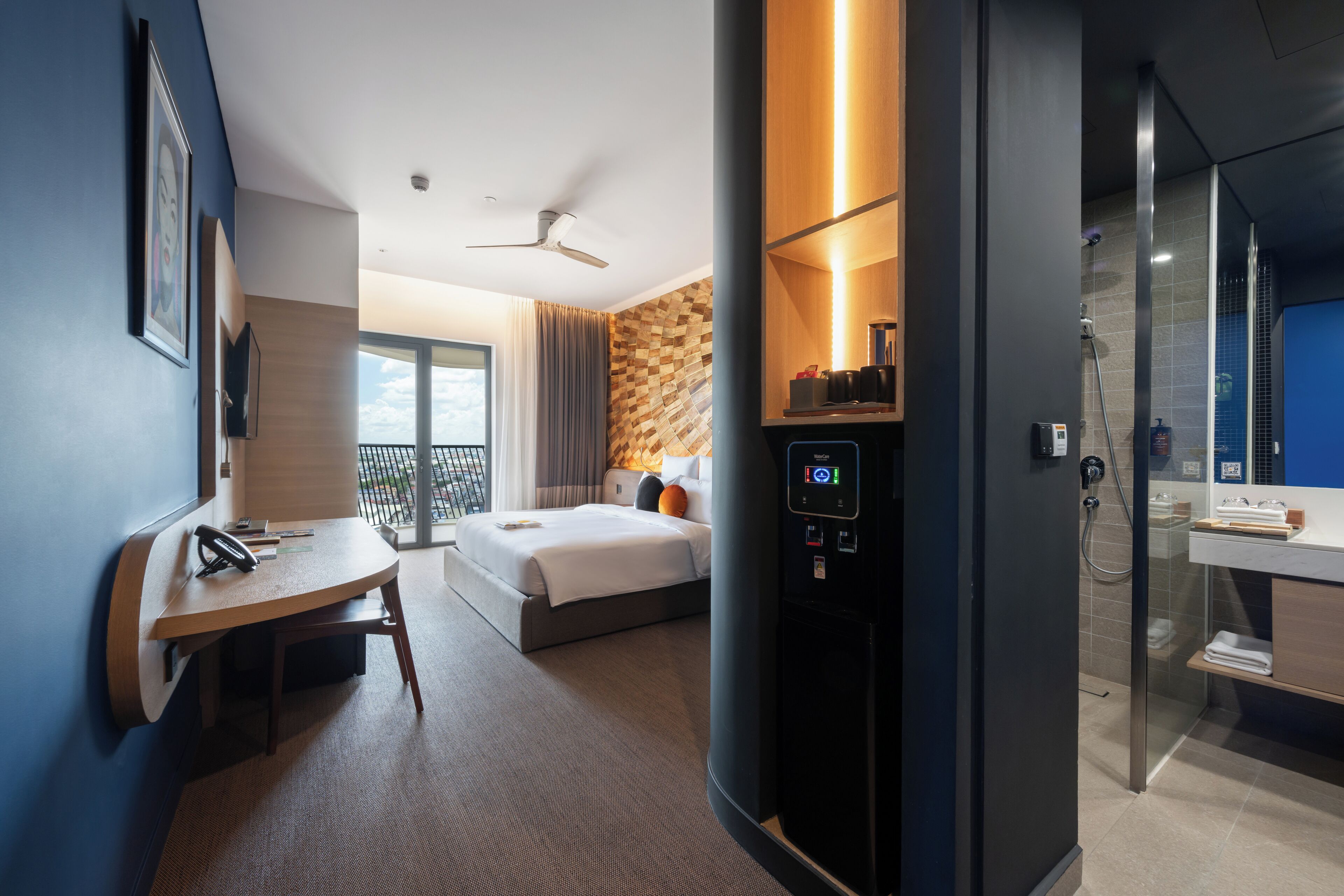 A hotel room with a bed, a desk, a shower, and a view of the outdoors.