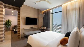 Una habitación de hotel moderna con una cama grande, un televisor de pantalla plana, un escritorio y un balcón con vista a la ciudad.
