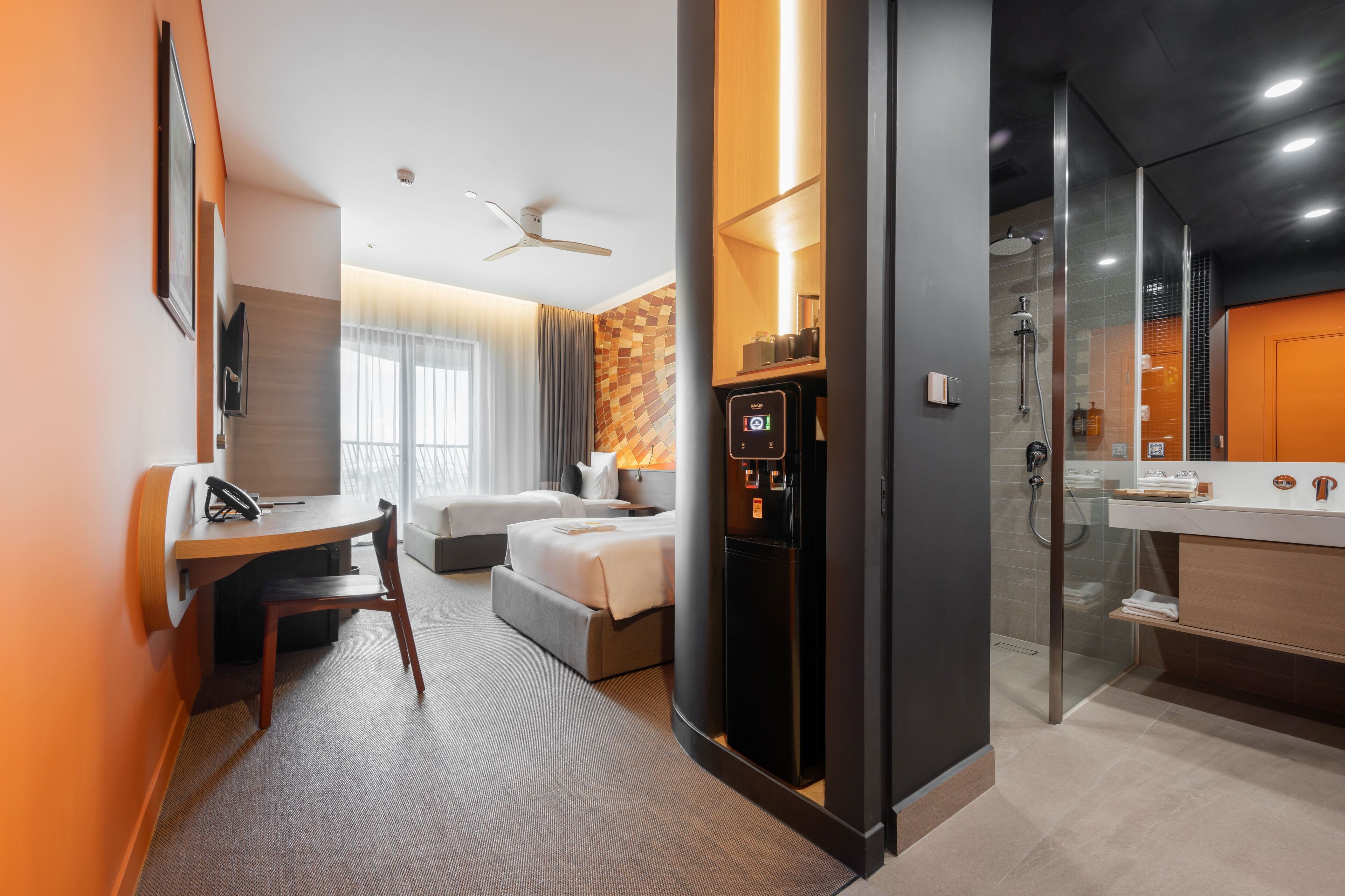 A hotel room with a desk, bed, and a minibar.