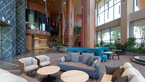 A spacious lobby with a modern design, featuring a large seating area with sofas and chairs, a coffee table, and a staircase leading to an upper level. - SUN & MOON, Riverside Hotel (Phnom Penh)