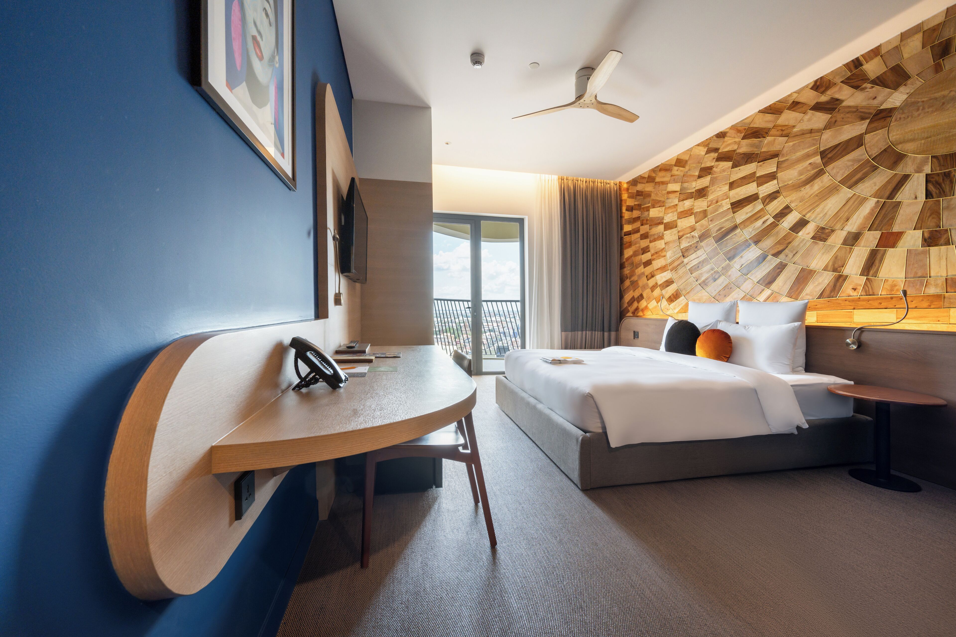 Ein modernes Hotelzimmer mit einer gebogenen Schreibtisch, einem großen Bett und einem einzigartigen Wanddesign aus Holz.