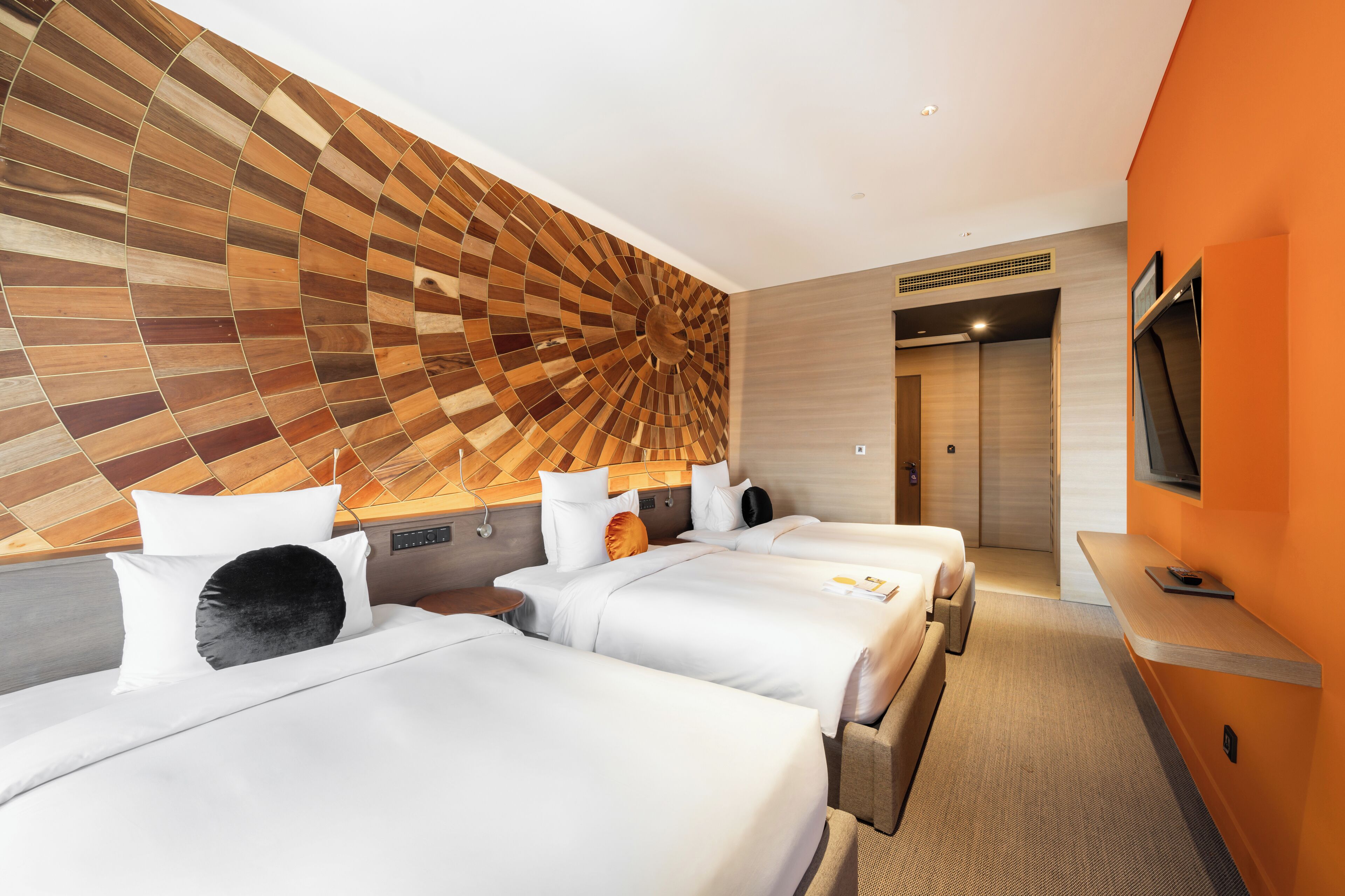 A hotel room with three beds, a large wall art piece, a TV, and a wooden headboard.