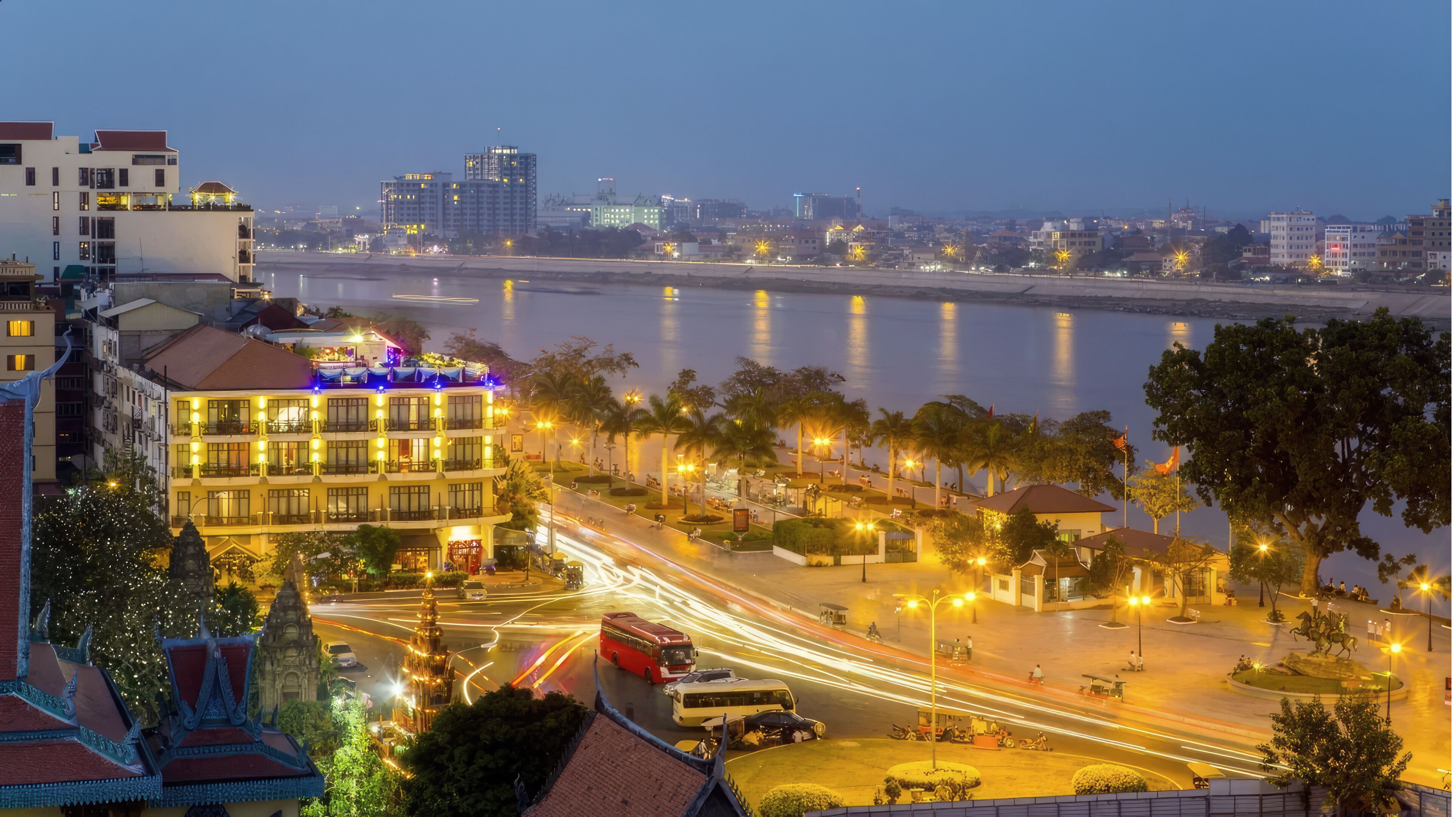 A riverside hotel with multiple floors, outdoor seating, and a view of the river.