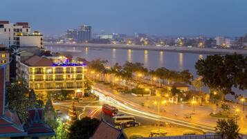 A riverside hotel with multiple floors, outdoor seating, and a view of the river.