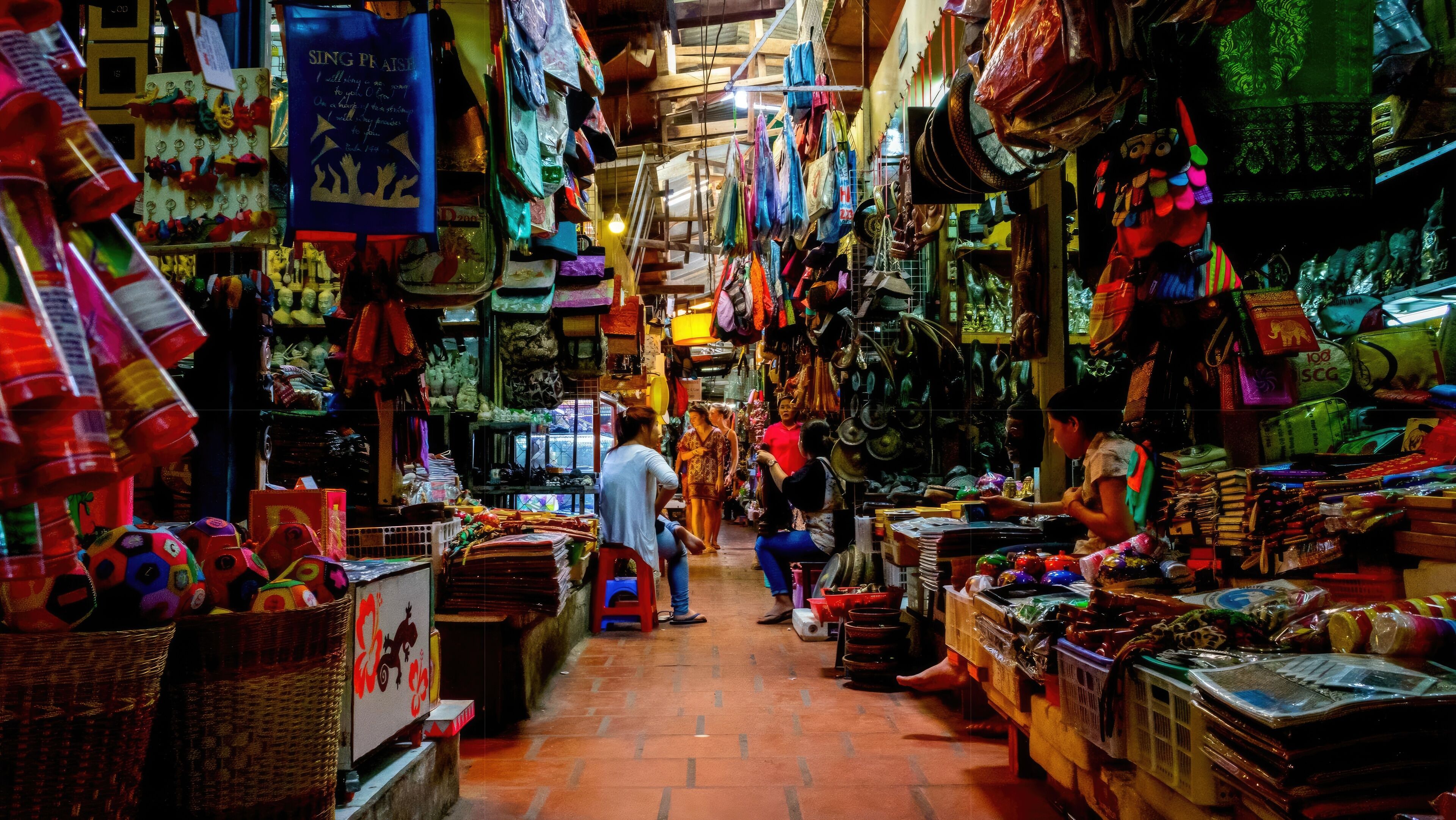 A narrow market with various stalls selling colorful items.