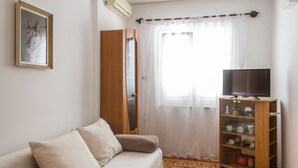 A room with a sofa, a television, a cabinet with dishes, and a window with curtains. - Simo A1, Punat (Punat)