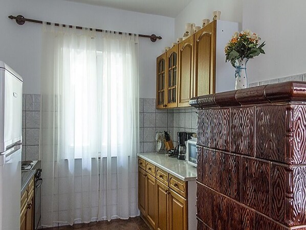 Eine Küche mit Holzschränken, einer weißen Arbeitsplatte und einem Edelstahlkühlschrank.
