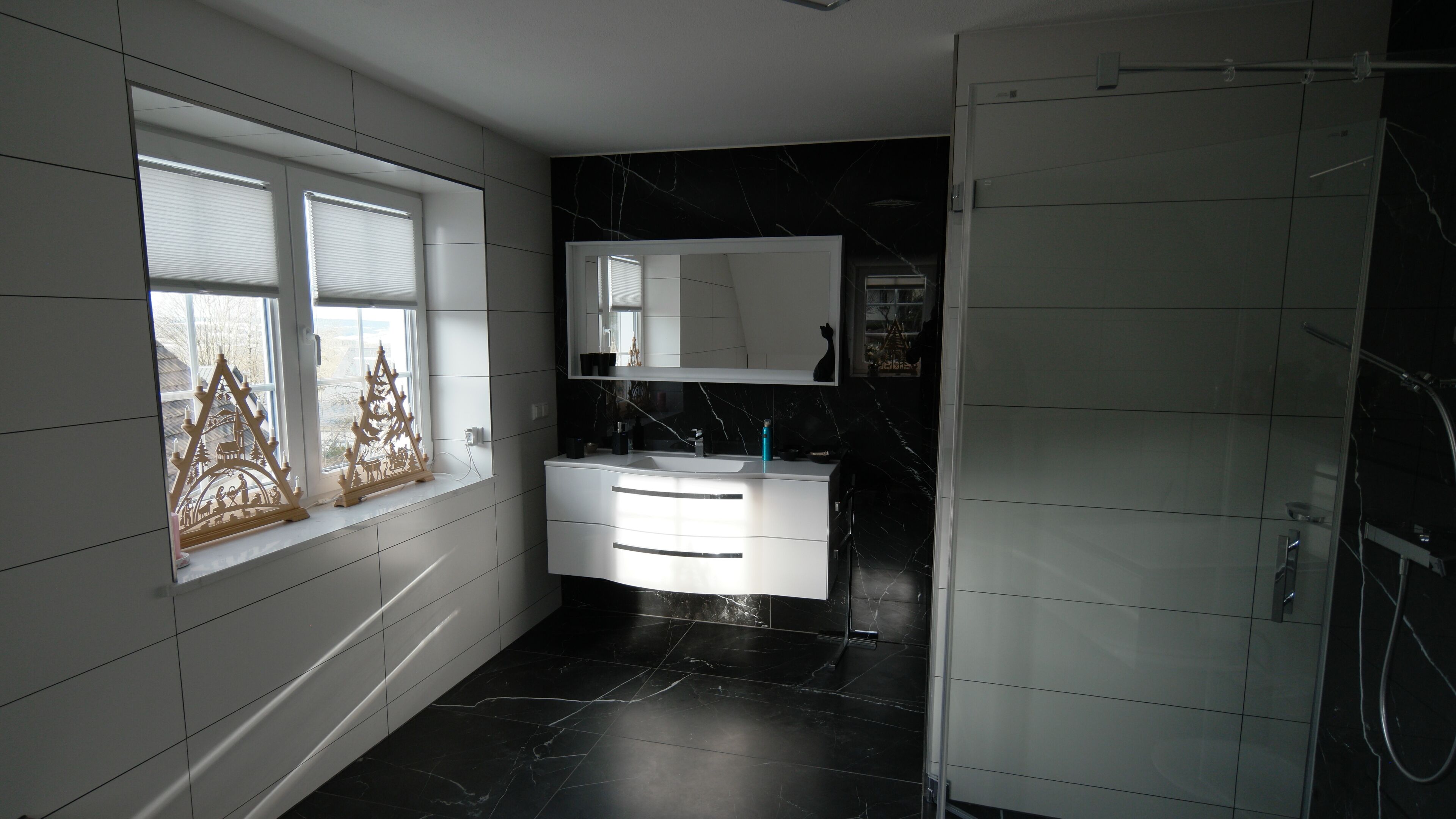 A bathroom with a white vanity, a large mirror, and a black marble floor.