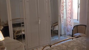 Une chambre à coucher avec un lit, une armoire, une chaise et une table avec une lampe.