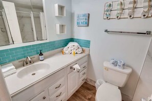 A bathroom with a white sink, a mirror, a towel rack, and a toilet.