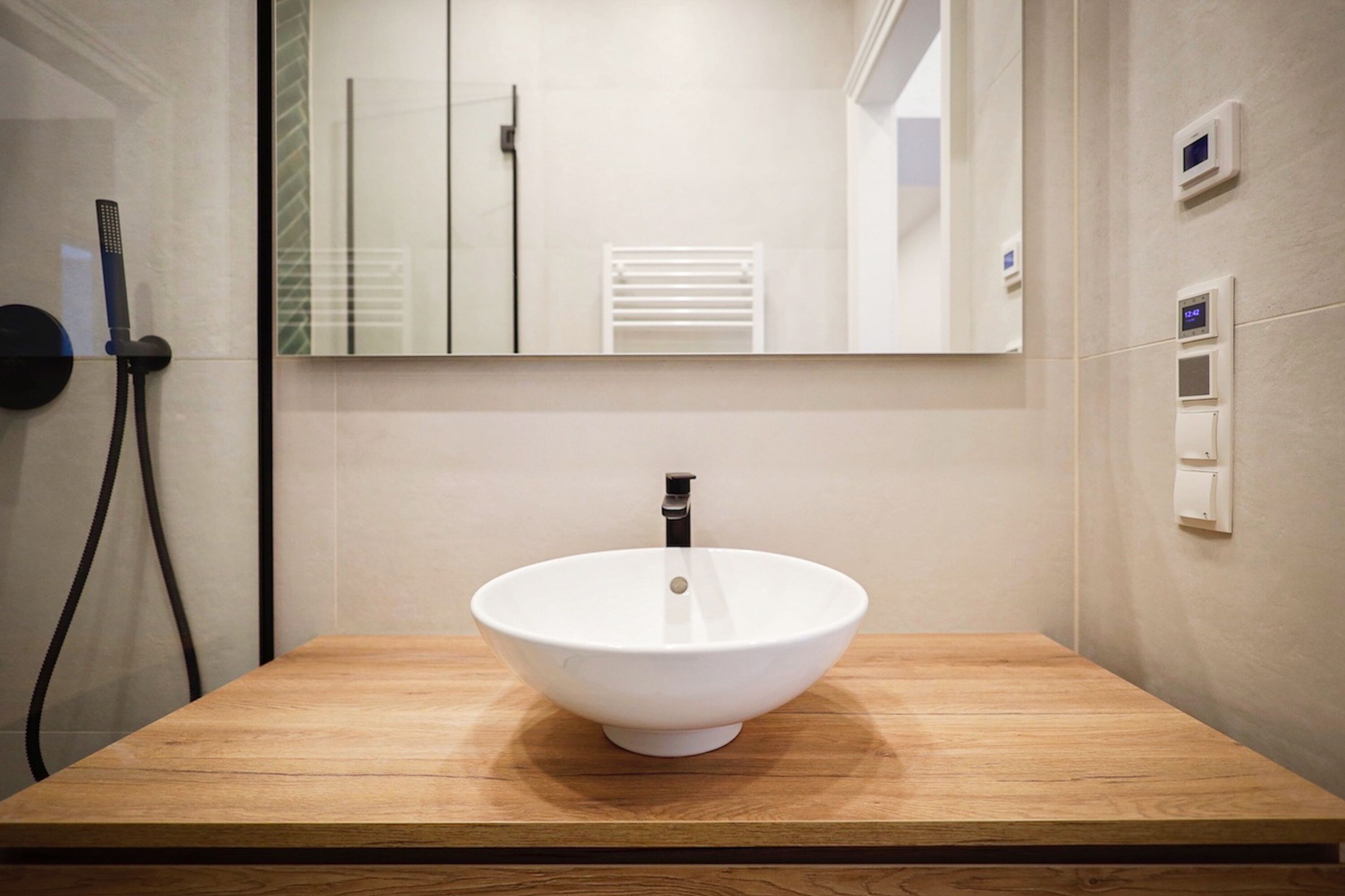 Un baño con tocador de madera, lavabo blanco, espejo y toallero.