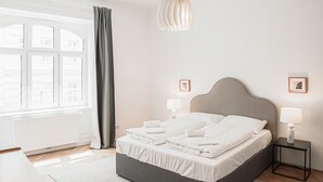 Un dormitorio moderno con una cama grande, lámparas de noche y vistas de la ciudad a través de una ventana.