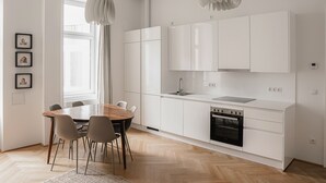 Una cocina moderna con armarios blancos, una mesa de comedor de madera y un horno negro.