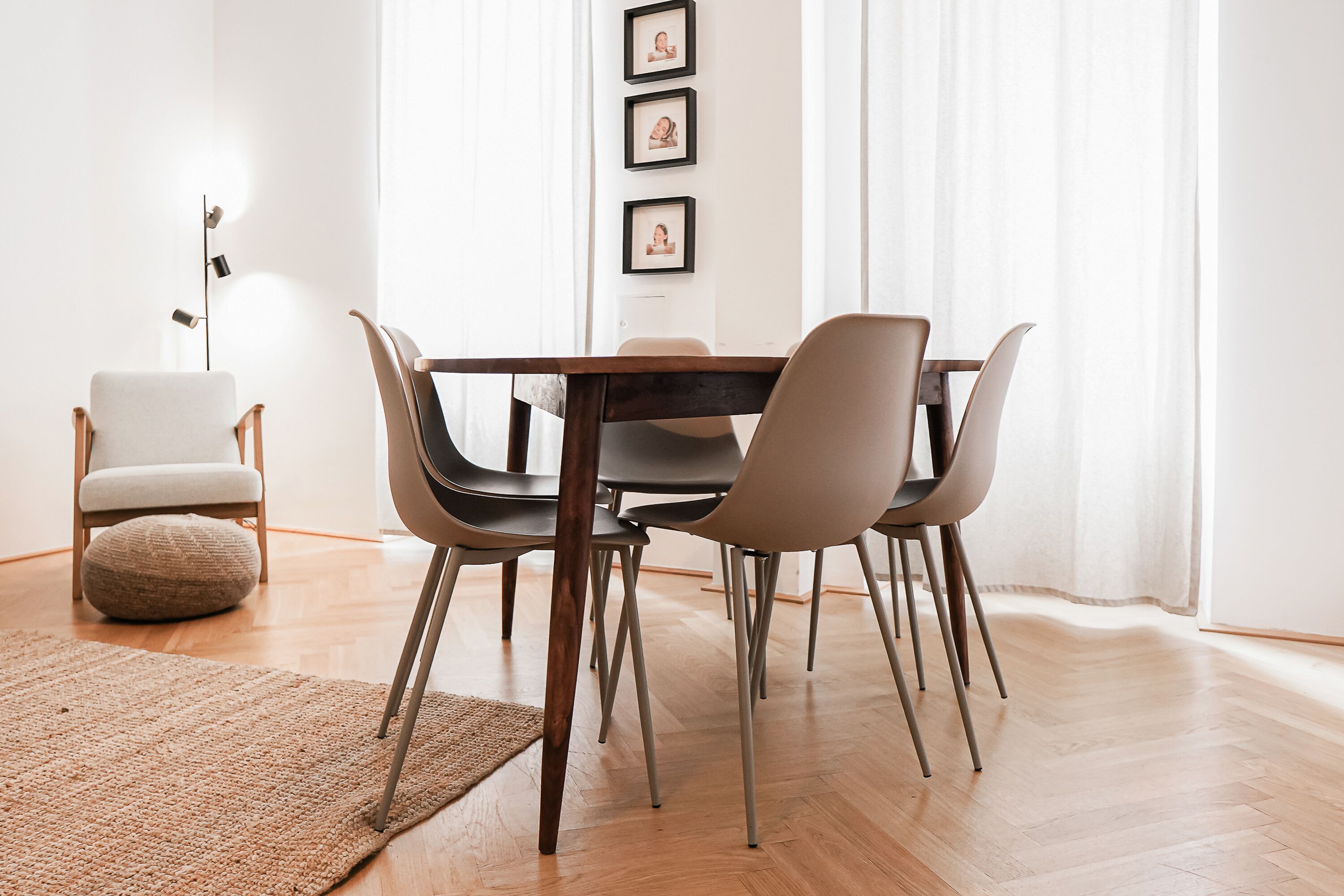 Ein Essbereich mit Holztisch, vier Stühlen, einem kleinen runden Teppich und einer Stehlampe.