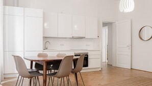 Una cocina moderna con armarios blancos, una mesa de madera y cuatro sillas.