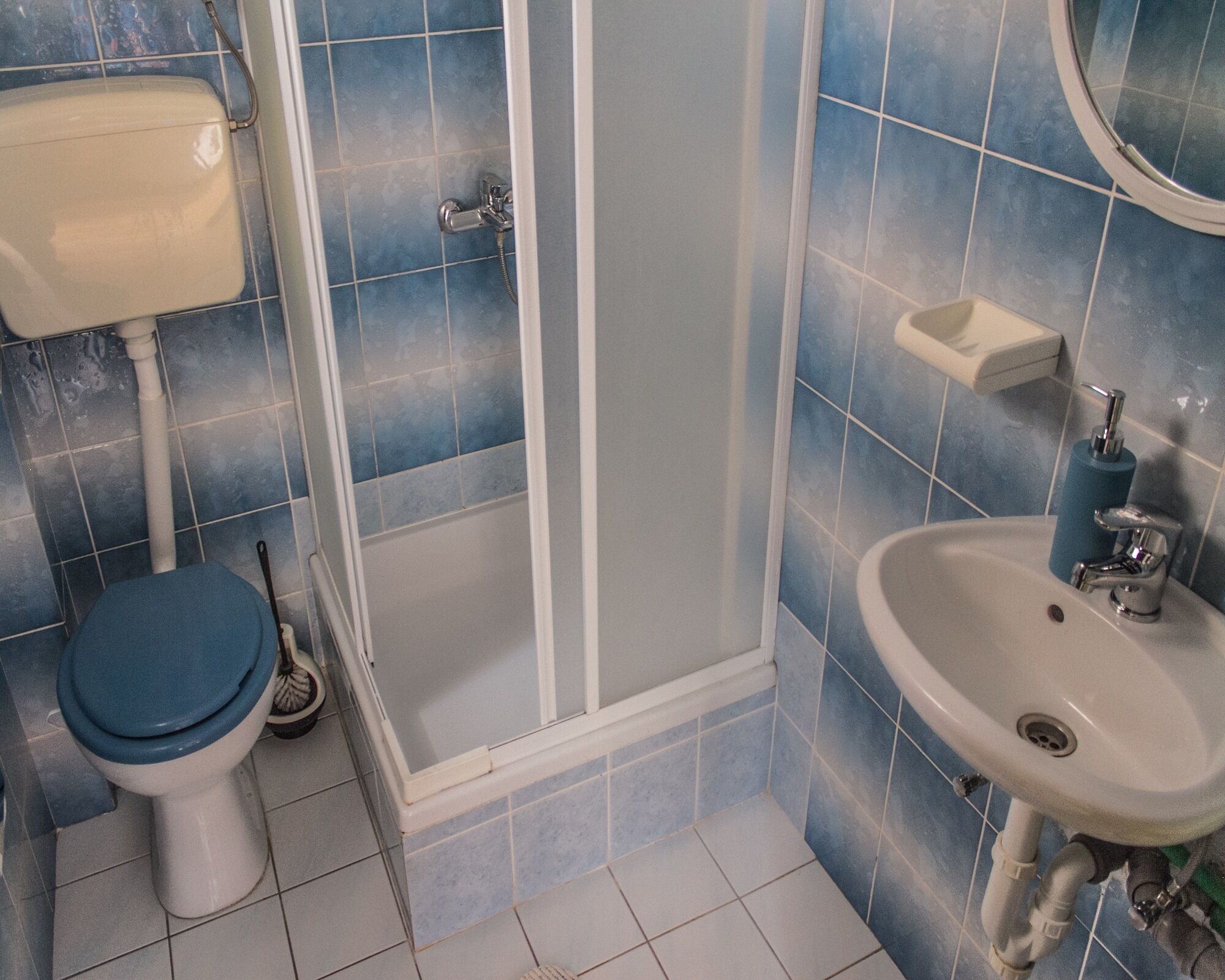 Een badkamer met toilet, douche en wastafel.