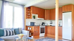 A modern kitchen with wooden cabinets, a white refrigerator, and a dining area with a glass table and sofa. - Apartments in Porvoo (Porvoo)