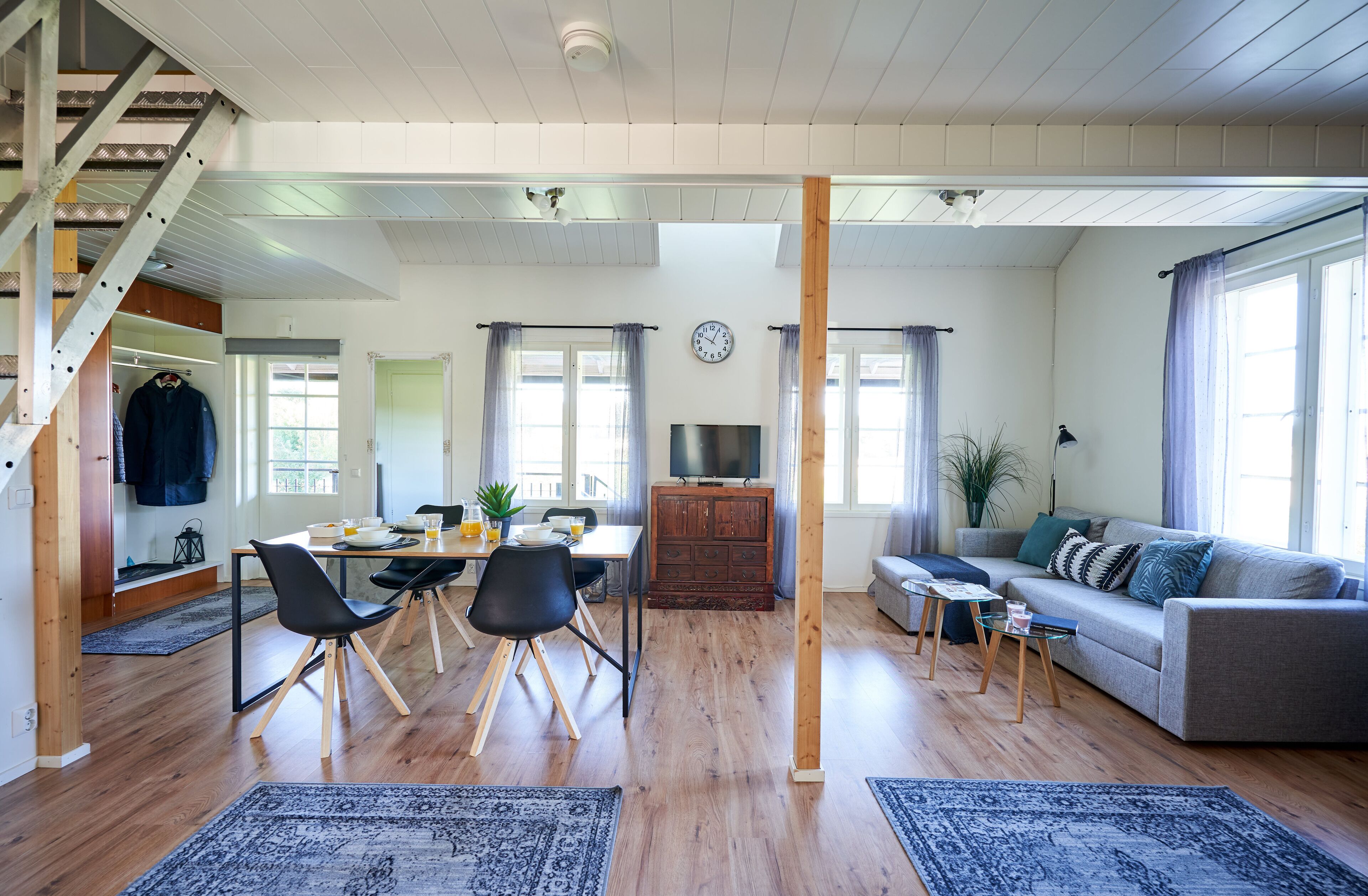 A spacious living area with a dining table, sofa, and staircase.