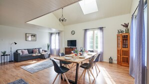 A spacious living room with a dining area, wooden flooring, a sofa, a TV, and a cabinet with glass doors. - Apartments in Porvoo (Porvoo)