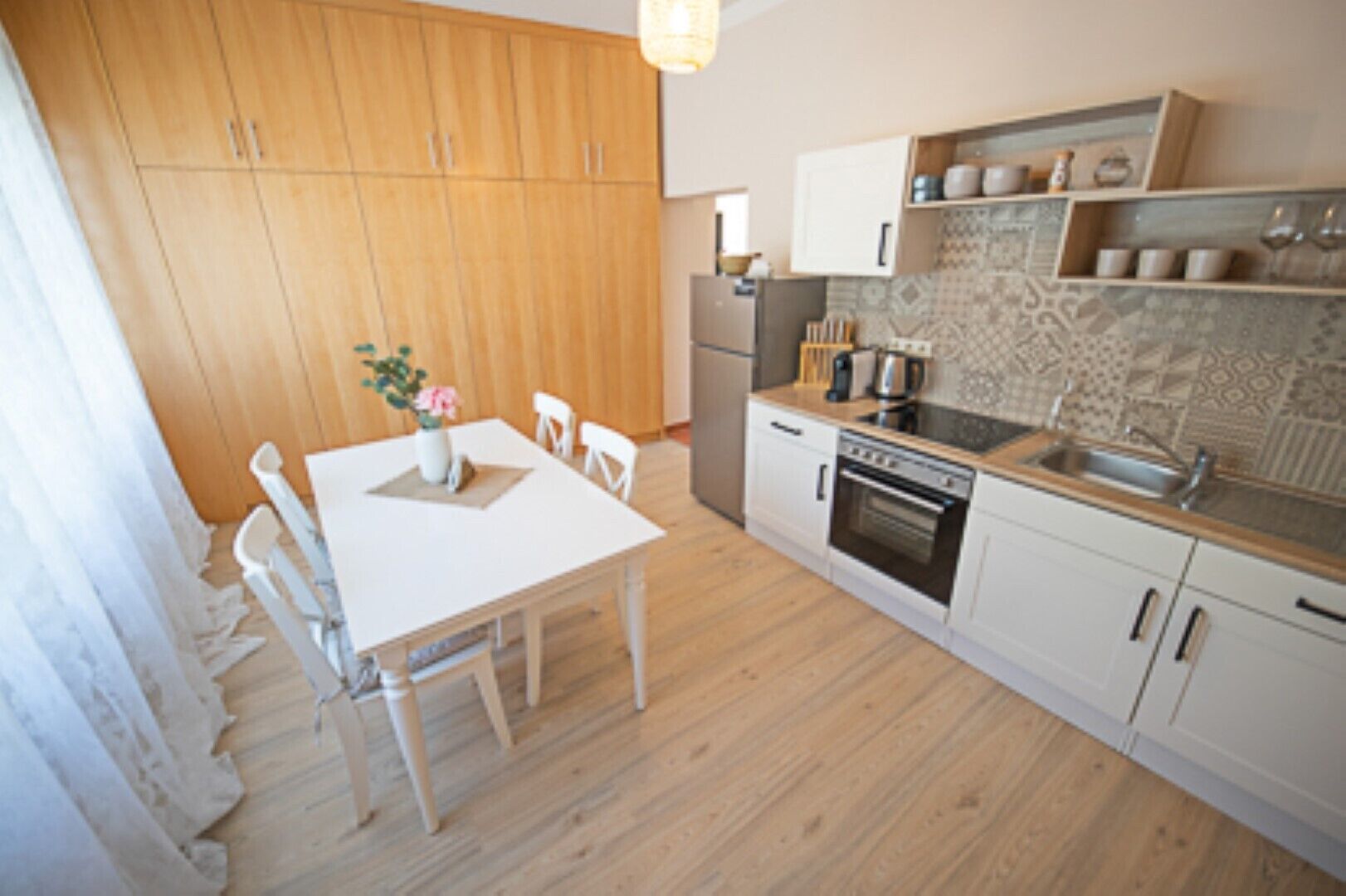 A compact kitchen with wooden cabinets, a white countertop, and a dining area with a table and chairs.