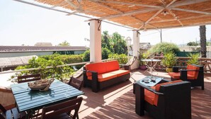 An outdoor patio with a thatched roof, a sofa, wicker furniture, and potted plants. - Villa With Large Garden Close to the Sea, Between Etna and Taormina (Acireale)