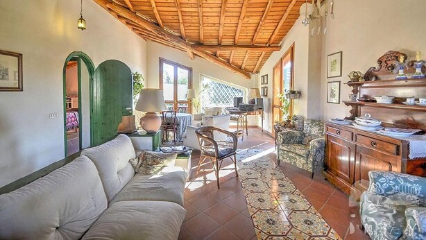 A spacious living room with a high wooden ceiling, a sofa, patterned rugs, and a dining area with chairs and a table. - Villa With Large Garden Close to the Sea, Between Etna and Taormina (Acireale)