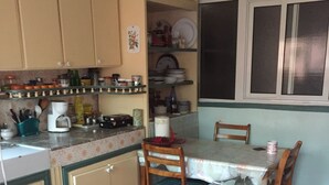 A kitchen with a dining table and chairs, a refrigerator, and a window with blinds. - Room-property Located in a Quiet Area cl (Casablanca)