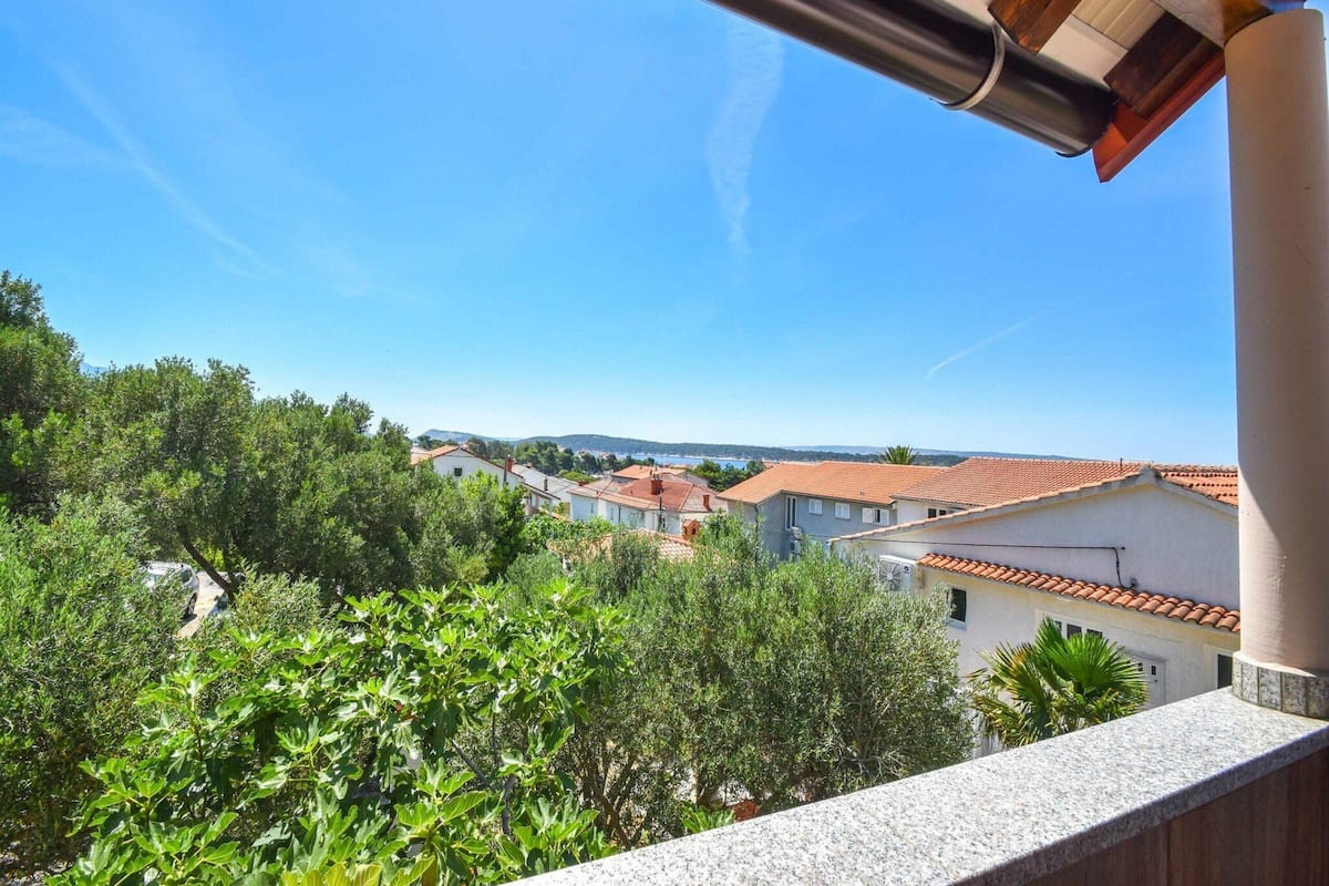 A balcony with a view of a residential area, including houses with red-tiled roofs and greenery.