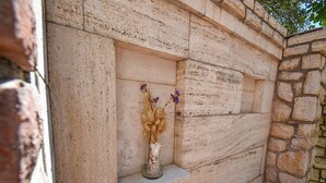 A stone wall with a built-in shelf holding a vase with dried flowers. - Apartments Jaklin (Rab)