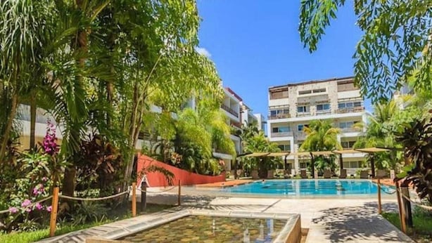 Un espace piscine offrant une vue dégagée sur un immeuble à plusieurs étages situé à l’arrière-plan.
