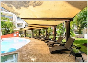 A poolside area with lounge chairs and a shaded canopy. - Sabbia Condos - Nice Apartment (Playa del Carmen)