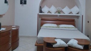 A bedroom with a bed, wooden dresser, and a ceiling fan. - Trullo Relais "La Perla Bianca" (Contrada Pozzomasiello-pentimi Locorotondo)