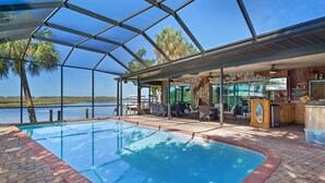 A pool area with a glass enclosure, a bar, and a view of the water.