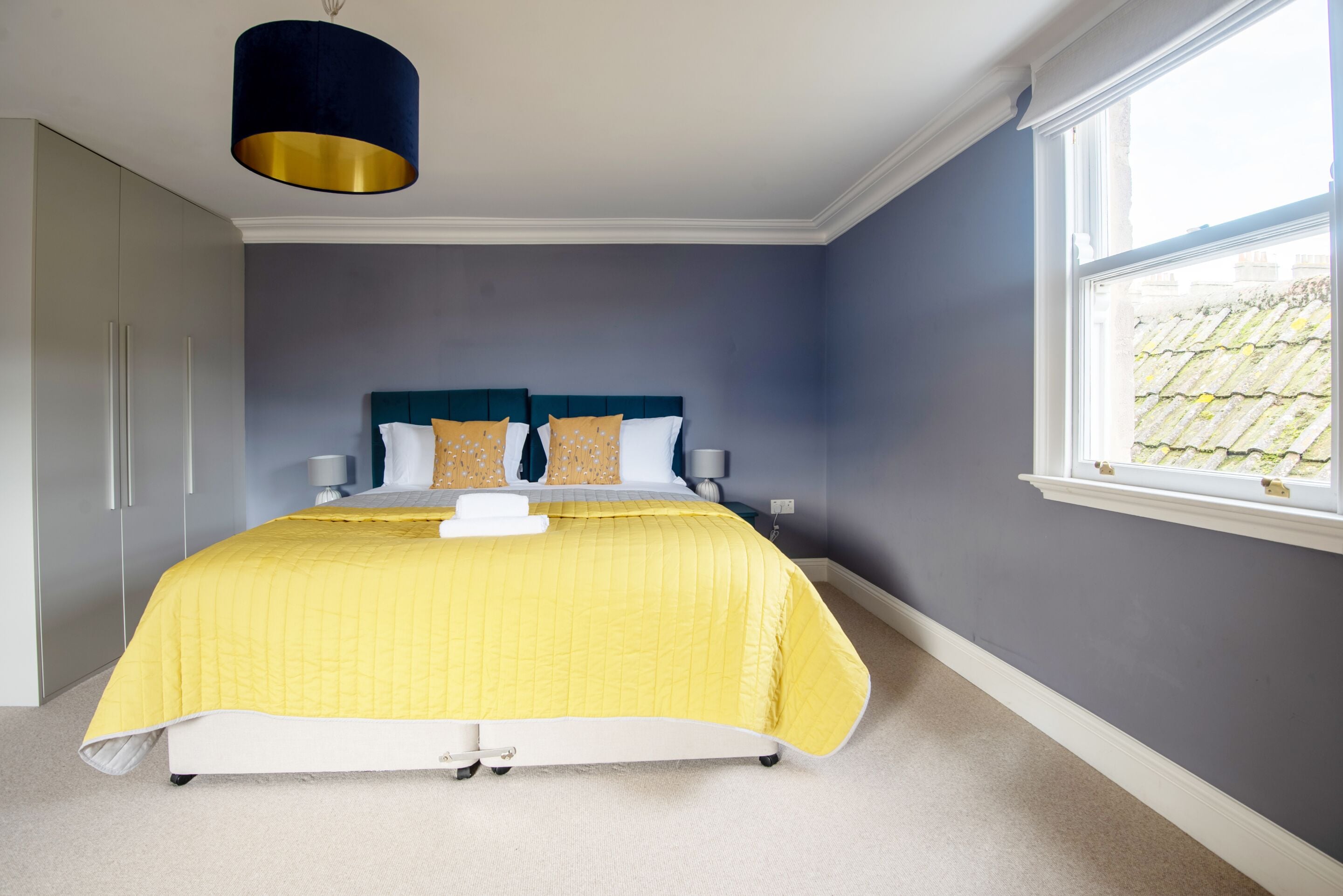 A bedroom with a bed, bedside tables, a window, and a wardrobe.