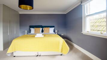 A bedroom with a bed, bedside tables, a window, and a wardrobe.
