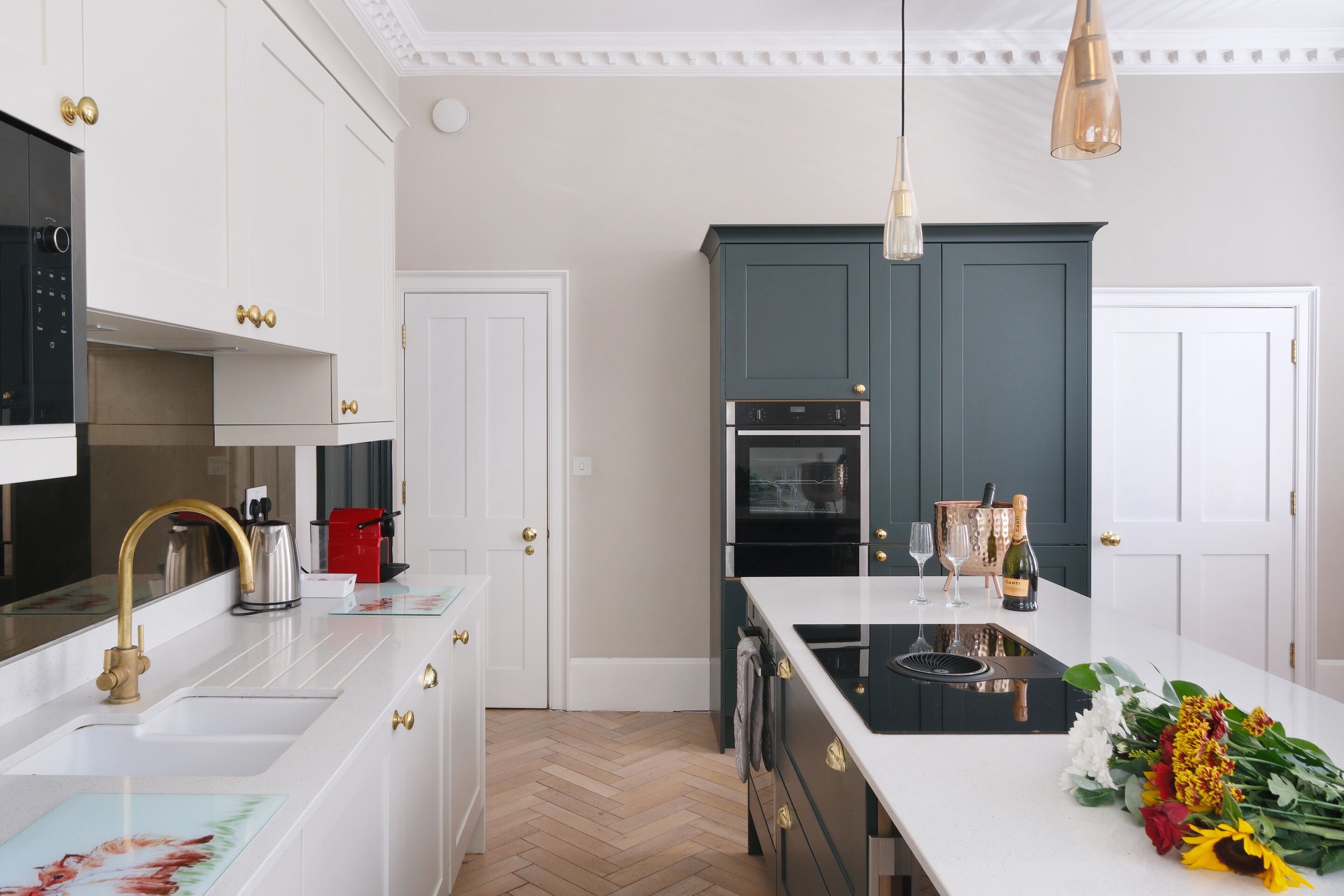 Una cocina moderna con armarios blancos, una isla central y un suelo de madera en espiga.