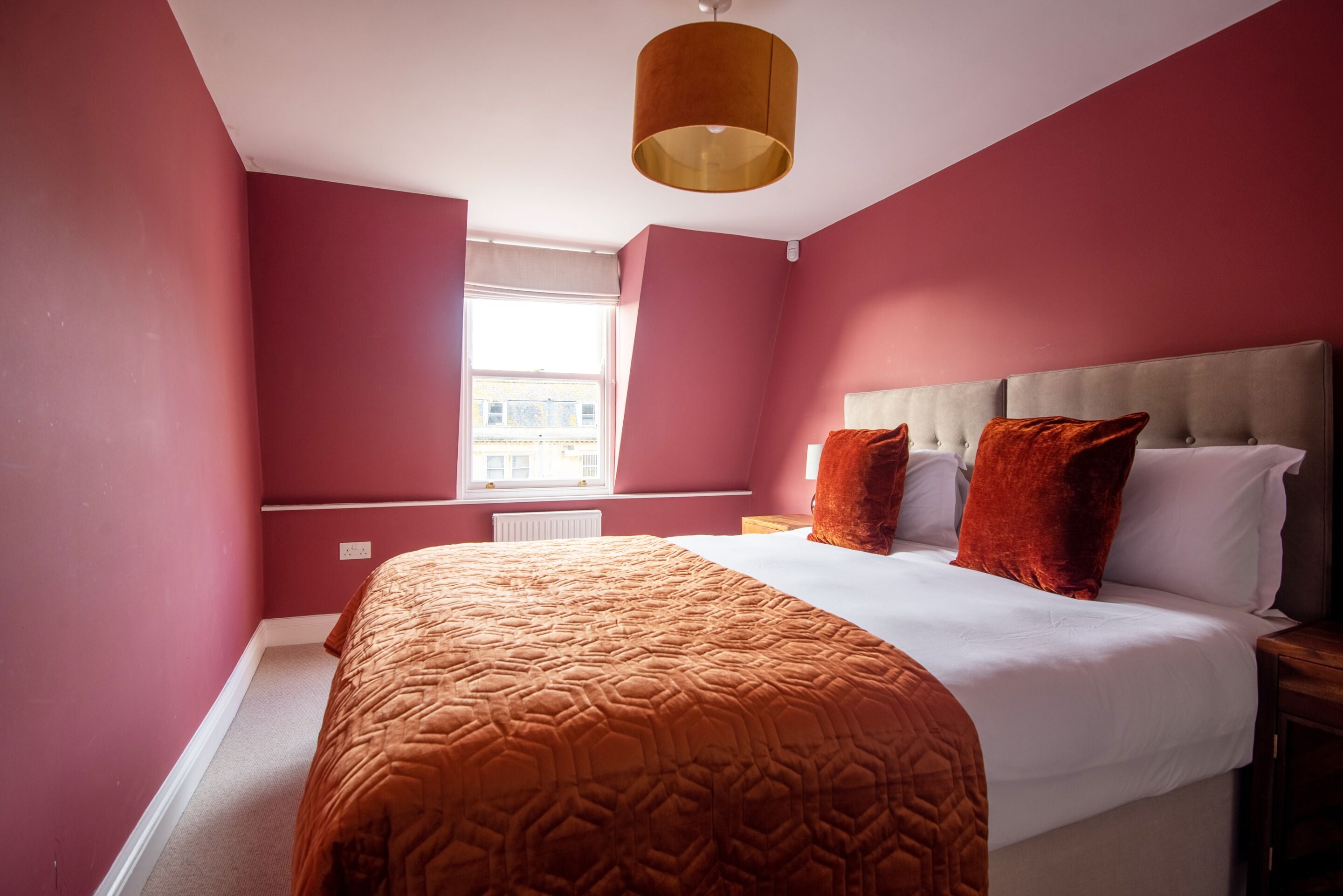 A bedroom with a large bed, a window with a view, and a ceiling light.