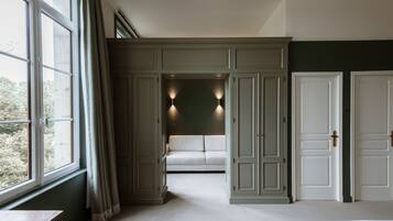 A bedroom with a large window, a sofa, and built-in wardrobes.