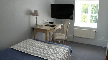 Une chambre à coucher avec un lit, un bureau, une chaise, une télévision et une fenêtre.