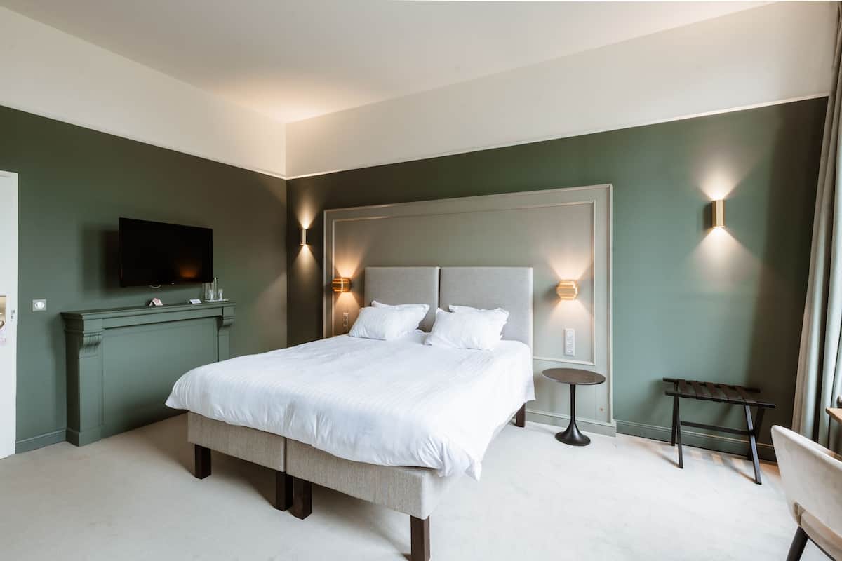 Een moderne hotelkamer met een groot bed, nachtkastjes, een flatscreen televisie en een zithoekje.