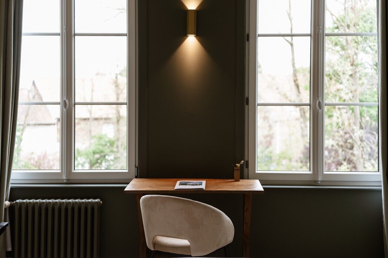A room with a desk, chair, and a window with a view of greenery.