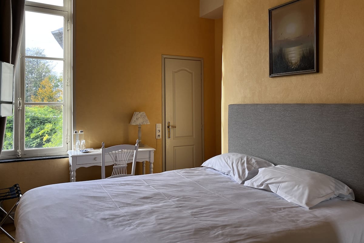 Een hotelkamer met een bed, een bureau, een stoel, een lamp en een deur.